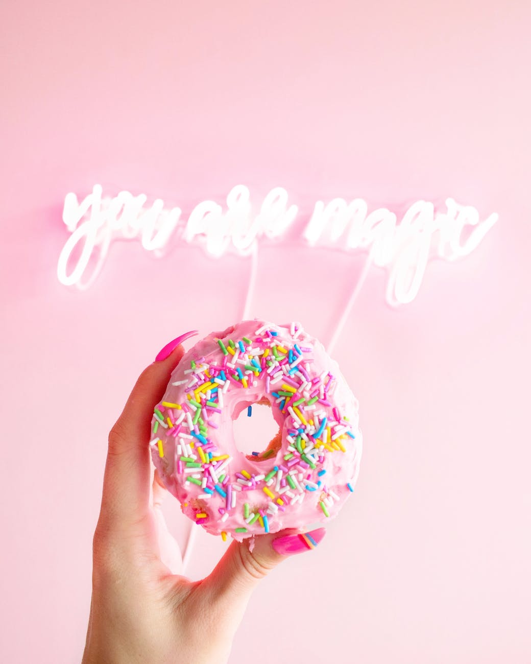 woman holding donut with sprinkles